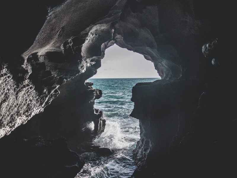 gray cave near body of water